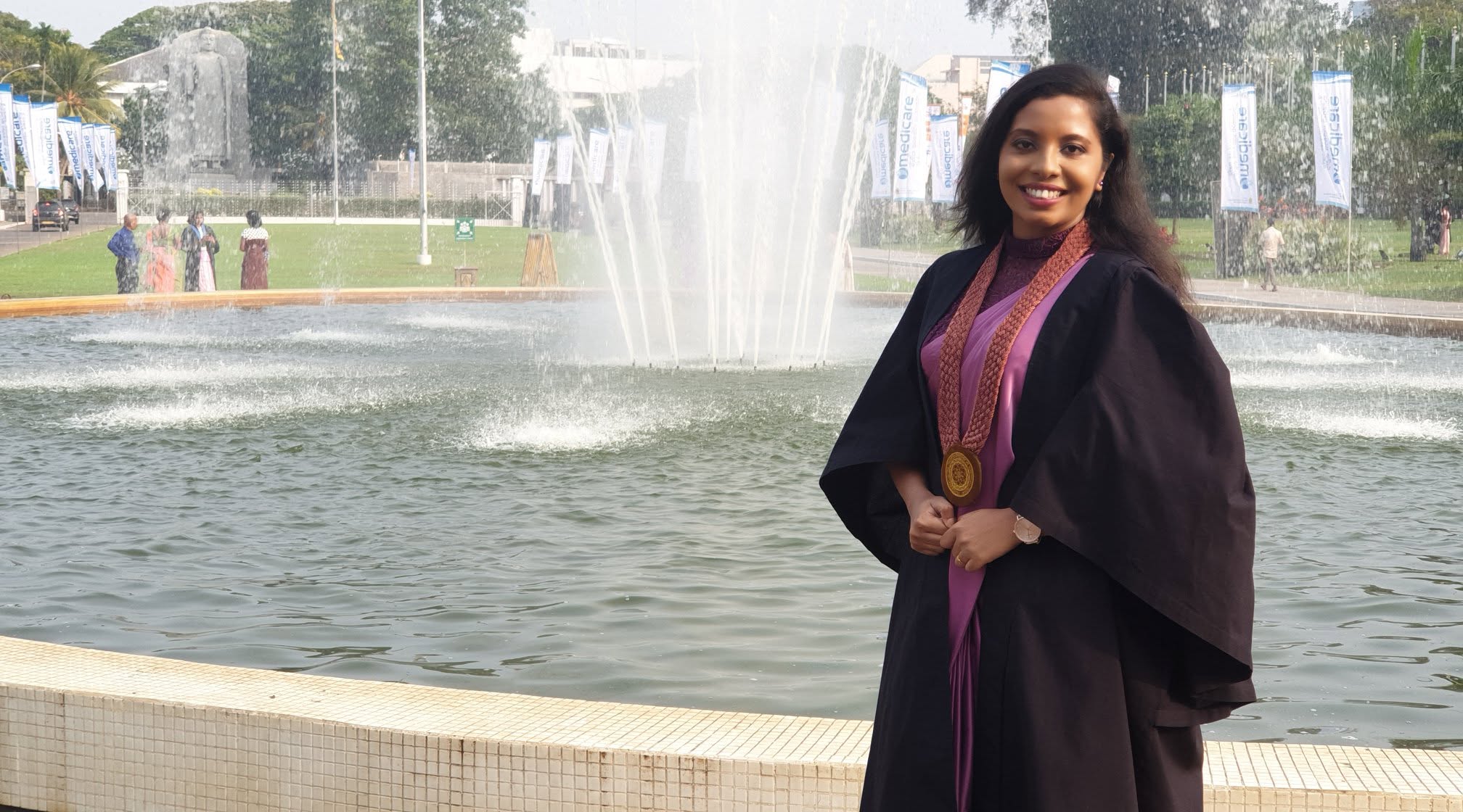 Sandani in graduation gown by a fountain, University of Kelaniya